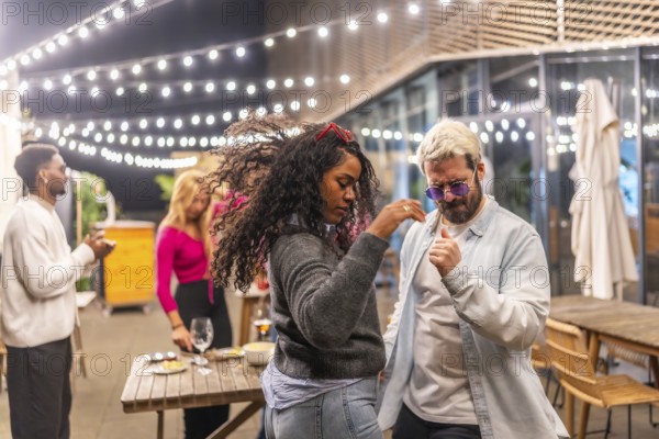 Multi-ethnic friends dancing salsa in the terrace of a night bar