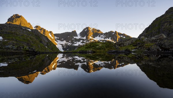 Rocky mountain peaks reflected in a small pond, mountain landscape with alpenglow at sunrise, at the Trollfjord Hytta, at the Trollfjord, Lofoten and Vesterålen, Nordland, Norway, Europe