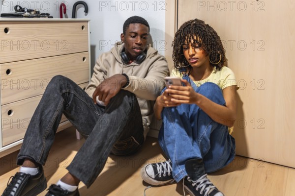 Two teenagers sitting on the floor of a cozy bedroom, using a smartphone and enjoying moments of connection and communication together