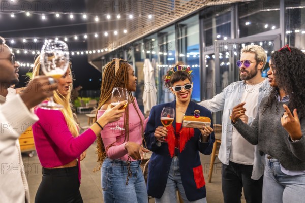 Multi-ethnic friends surprising woman with birthday cake at bar terrace at night
