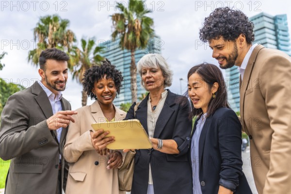 Mature businesswoman using digital tablet while talking with multi-ethic business colleagues during outdoor meeting