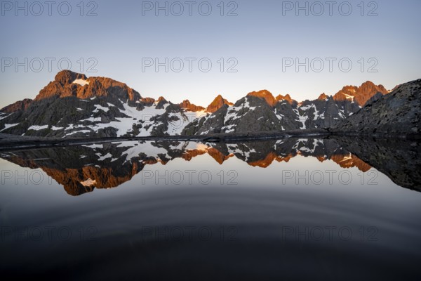 Rocky mountain peaks reflected in a small pond, mountain landscape with alpenglow at sunrise, at the Trollfjord Hytta, at the Trollfjord, Lofoten and Vesterålen, Nordland, Norway, Europe