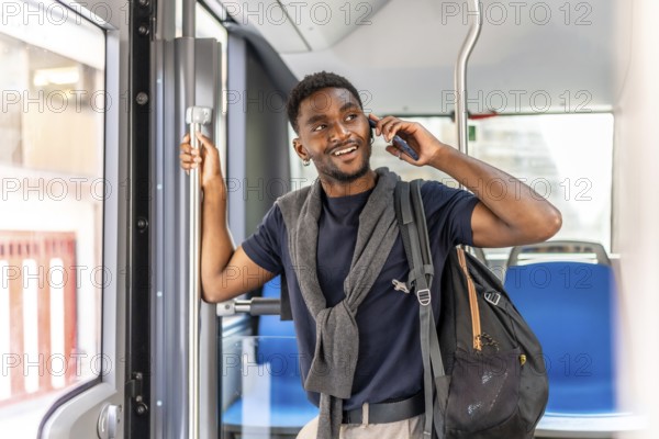 Young african businessman talking to the cellphone smiling and standing on the bus