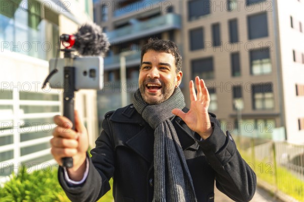 Male caucasian elegant mature vlogger waving while explaining something to the audience streaming in the city