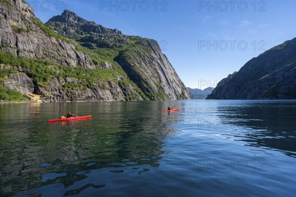 Two kayakers with red kayaks in the fjord Trollfjord, mountains reflected in the water, fjord landscape and mountains, Lofoten, Nordland, Norway, Europe