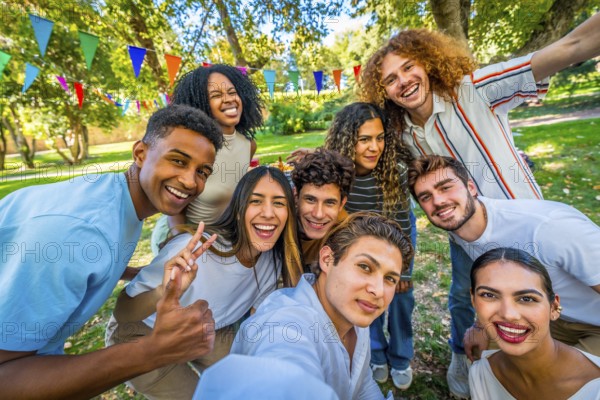 Frontal personal perspective view of happy young multi-ethnic students taking selfie celebrating party in a park