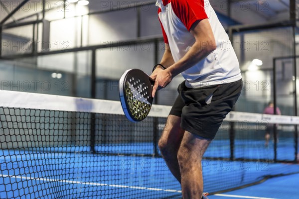 Cropped photo of an unrecognizable sportive man playing paddle tennis indoors