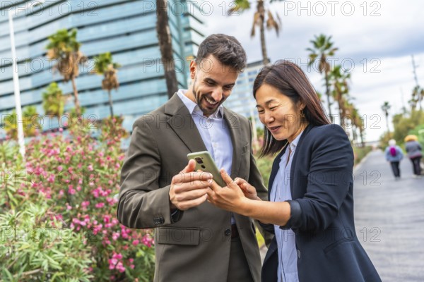 Happy multi-ethnic business people using mobile and smile standing in a financial district in a tropical city
