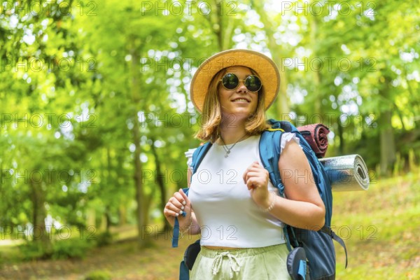 Smiling female backpacker day dreaming among greenery in the forest
