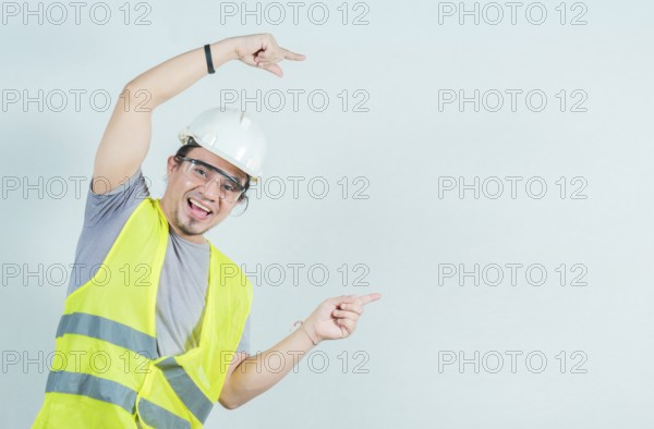 Happy young builder pointing an advertisement isolated. Smiling handsome engineer pointing to the side with both fingers isolated