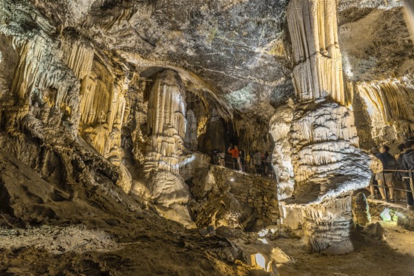 Tourists admiring giant stalactites and stalagmites inside the famous postojna cave, a major tourist attraction in slovenia