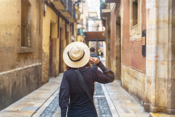 Tourist with straw hat walking in the medieval city of tarragona, spain, enjoying the historical architecture