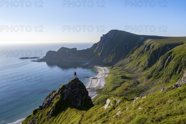 Climber on a rock, view of picturesque coastal landscape, steep coast with peak Måtind or Måtinden, Høyvika beach and sea, hike to the summit of Måtind, Andøya island, Vesterålen, Nordland, Norway, Europe