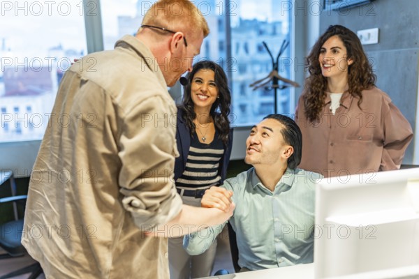 Business team congratulating their colleague on a successful project, shaking hands in the office workplace