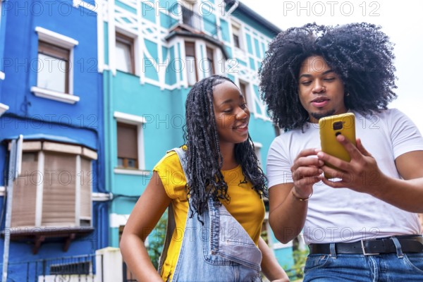 African couple looking for directions with the mobile exploring a city with colorful facades