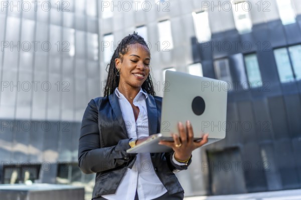 Portrait of a beauty confident latin businesswoman standing using laptop outside a financial building