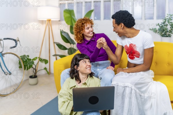 Transgender person and lesbian couple having fun using laptop together at home
