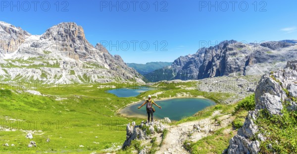 Tourist enjoying the scenic view of tre cime di lavaredo and alpine lakes on a sunny summer day in the italian dolomites. Laghi dei Piani