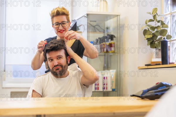Reflection on the mirror of a modern hairdresser and satisfied man with new capillary prosthesis in the salon
