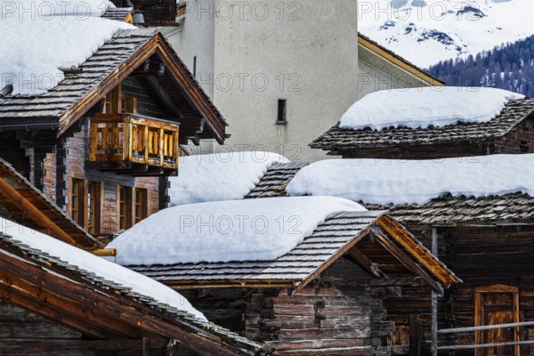 Old wooden houses with snow-covered roofs and the Saint Theodule church in the historic village centre, Grimentz, Val d'Anniviers, Valais Alps, Canton Valais, Switzerland, Europe