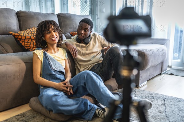 Two influencers are recording a vlog in their living room, discussing lifestyle and fashion tips for their online audience