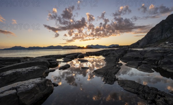 Clouds reflected in a small pond on a rocky coast, coastal landscape at sunset, Henningsvær, Lofoten, Nordland, Norway, Europe