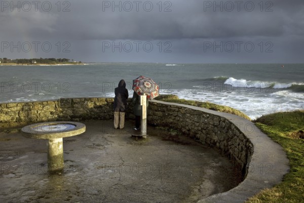 Tourists looking at sea in bad weather from the Pointe de Combrit near Bénodet, Finistère, Brittany, France, Europe