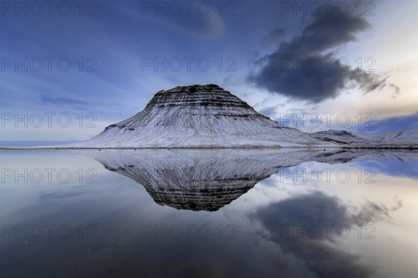 Kirkjufell, nunatak hill covered in snow reflected in water of fjord on the Snæfellsnes peninsula in winter, most photographed mountain in Iceland
