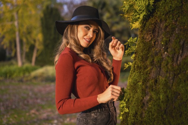 Lifestyle, portrait of a caucasian girl in a black hat at sunset in a green park