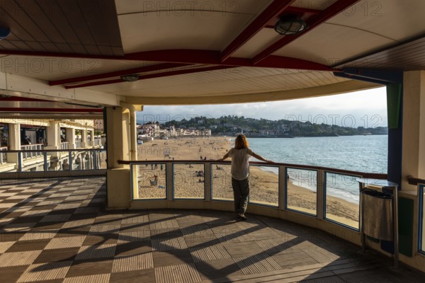 A young woman looking at the beautiful Grande Plage in Saint Jean de Luz at sunset, vacation in the south of France, French Basque Country. France