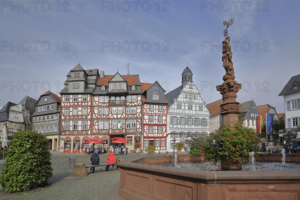 Historic half-timbered houses and market fountain, Haus Zum goldenen Löwen built in 1709 with slate roof, bench with people, town hall, market square, Butzbach, Wetterau, Hesse, Germany, Europe