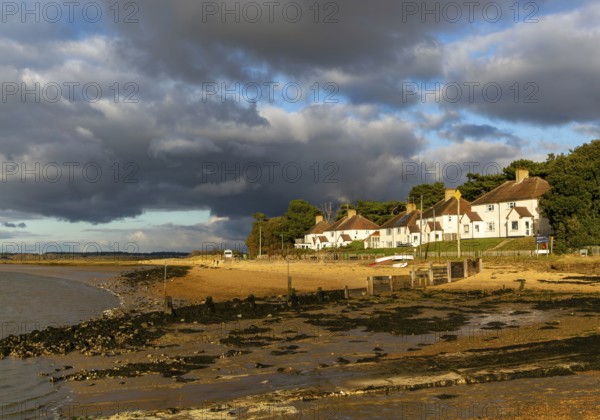 Storm clouds over beach and buildings at Bawdsey Quay, Suffolk, England, UK