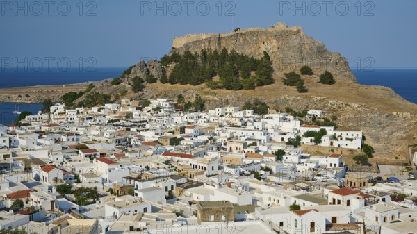 Clear daytime view of a coastal town with traditional Mediterranean architecture under a fortress, Acropolis of Lindos, Lindos, Rhodes, Dodecanese, Greek Islands, Greece, Europe