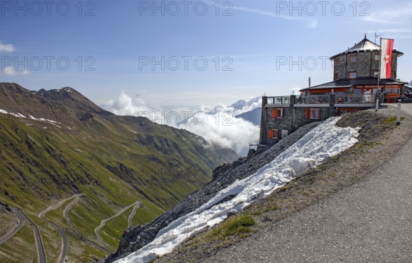 Right historic mountain hotel Hotel Restaurant Bar Gasthof Alpengasthof in Tibetan architectural style Tibetan house in front Flag Flag of South Tyrol at 2800 metres above sea level in the background East ramp North ramp Ascent to Alpine pass Alpine pass road Pass road with serpentines tight bends Stelvio Pass Stelvio, Stelvio, South Tyrol, Alto Adige, Italy, Europe