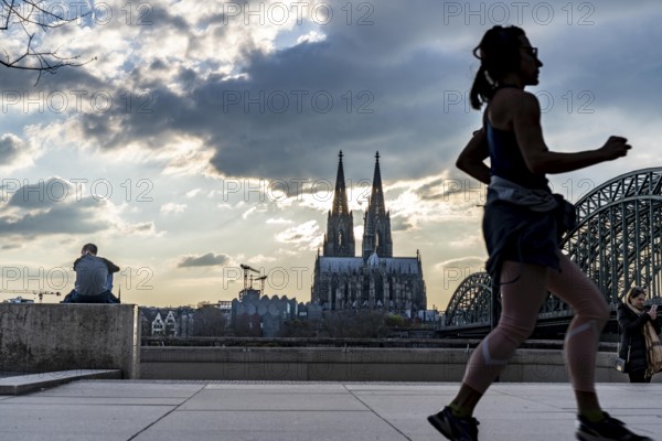 Panorama, Skyline of Cologne, with the cathedral and the railway bridge, Hohenzollern Bridge, on the Rhine, sunset, jogger, North Rhine-Westphalia, Germany, Europe