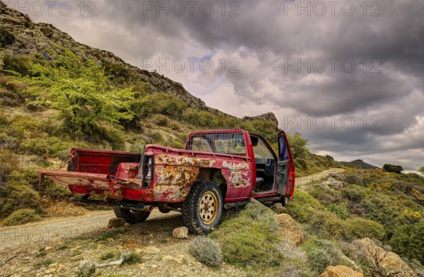 An old, rusty pickup truck in mountainous nature under a cloudy sky, wrecked vehicle, Crete, Greek Islands, Greece, Europe
