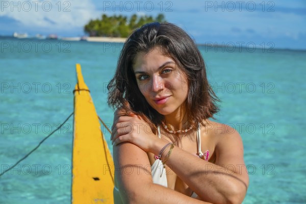 Young woman relaxing on traditional outrigger boat, enjoying the turquoise waters of daku island in siargao, philippines