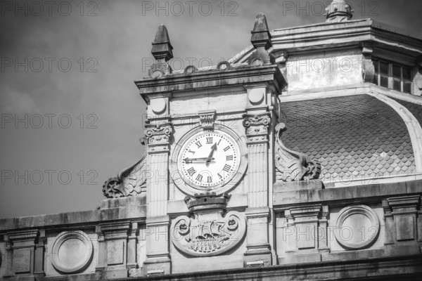 Black and white image of an ornate clock tower atop a historic building, showcasing intricate architectural details and classic design, San Sebastian City Hall, Basque Country
