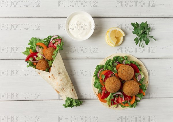 Tortillas, wrapped falafel balls, with fresh vegetables, vegetarian healthy food, on a wooden white background, no people, selective focus