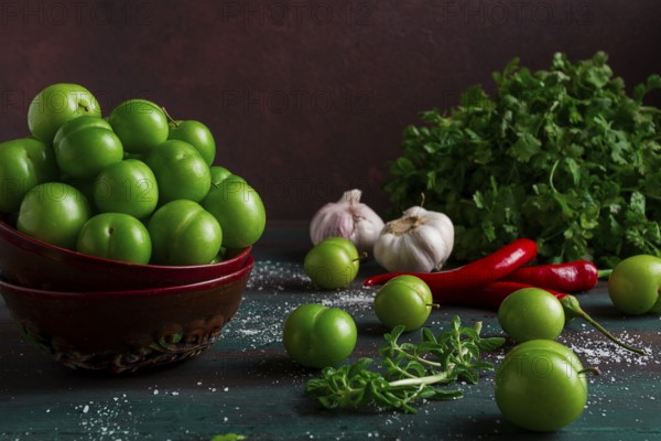 Tkemali, green cherry plum, with ingredients for sauce, cilantro, mint, hot pepper, garlic, on a wooden table, close-up, rustic, food background, no people, selective focus