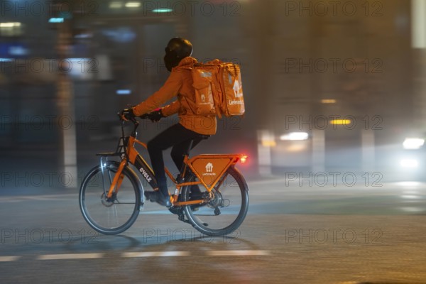 Lieferando courier, Lierferdienst cyclist, darkness, inner city traffic, fog, autumn, winter, North Rhine-Westphalia, Germany, Europe
