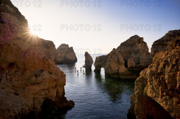 Stand up paddlers on their boards, kayakers, colourful cliffs and sunrise, rocks in the sea, Ponta da Piedade, Lagos, caves, cliffs, Atlantic Ocean, Algarve, Portugal, Europe