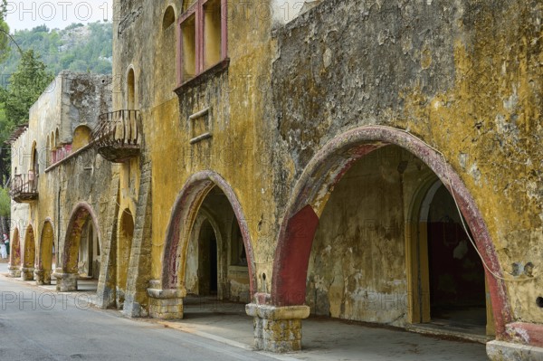 Street with dilapidated yellow historic-style buildings characterised by arches, balconies and peeling plaster, Italian Governor's Palace, Ruins, Italian colonial settlement, Eleousa, Rhodes, Dodecanese, Greek Islands, Greece, Europe