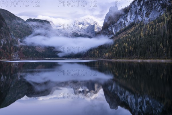 The Vordere Gosausee lake in autumn with a view of the Dachstein mountain range. The Gosaukamm on the right. Blue sky and clouds. In the evening after sunset. Reflection. Vorderer Gosausee, Gosau, Gosau valley, Salzkammergut, Upper Austria, Austria, Europe