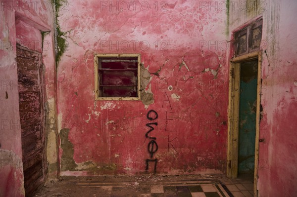Pink-painted room with graffiti on the walls, exposed to severe decay and ageing due to damaged doors and windows, Italian governor's palace, ruins, Italian colonial settlement, Eleousa, Rhodes, Dodecanese, Greek Islands, Greece, Europe