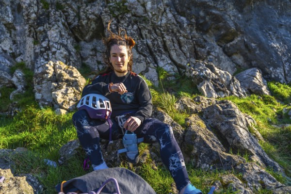 Young climber woman resting on a mountain after her climbing activity, checking her smartwatch