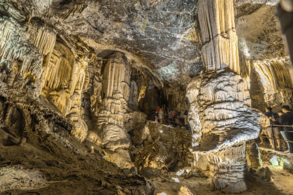 Tourists admiring the stalactites and stalagmites inside the famous postojna cave, a popular tourist attraction in slovenia