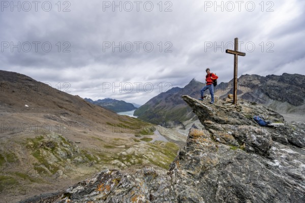 Mountaineer on rock with summit cross, summit behind the Labane des Dix, Valais Alps, Valais, Switzerland, Europe