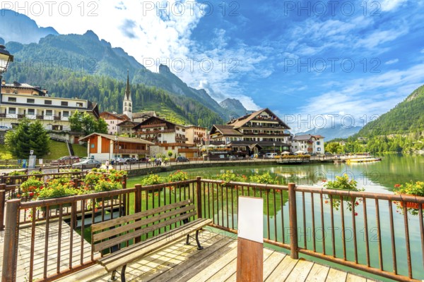 Tourists strolling along the picturesque shores of alleghe lake in the stunning dolomites on a beautiful summer day, enjoying nature's beauty