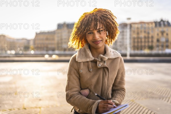 Beauty latin woman sketching on notebook sitting in the city